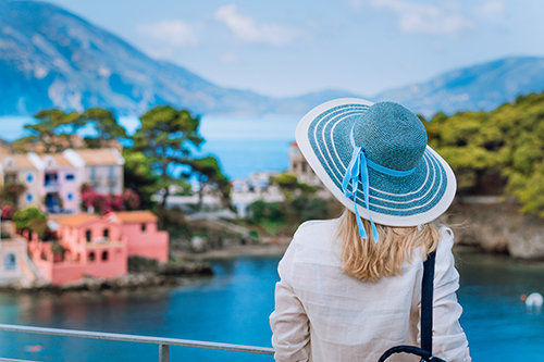 A woman looking at trees, a body of water, and houses A woman looking at trees, a body of water, and houses