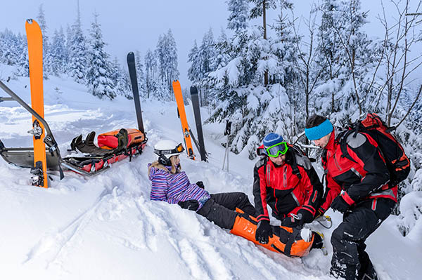 Un skieur couché dans la neige, assisté par du personnel médical Un skieur couché dans la neige, assisté par du personnel médical